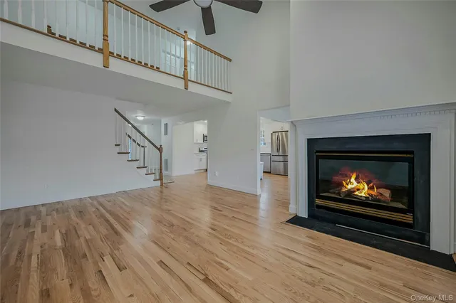 a view of an empty room with wooden floor a fireplace and a window