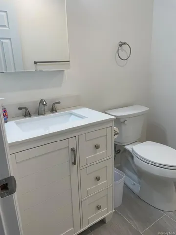 a bathroom with a granite countertop toilet sink and mirror