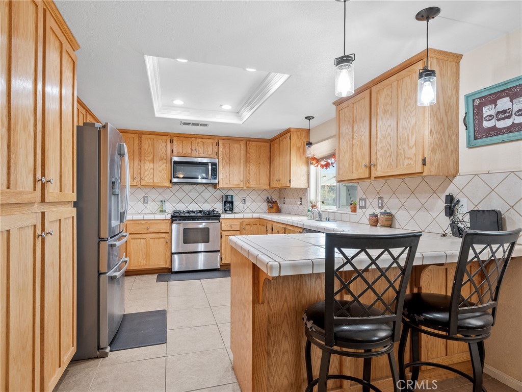 13776 Natoma Road Apple Valley, CA 92307 - Photo 19 of 40 a kitchen with stainless steel appliances granite countertop a stove a sink dishwasher a microwave oven and a refrigerator with wooden cabinets