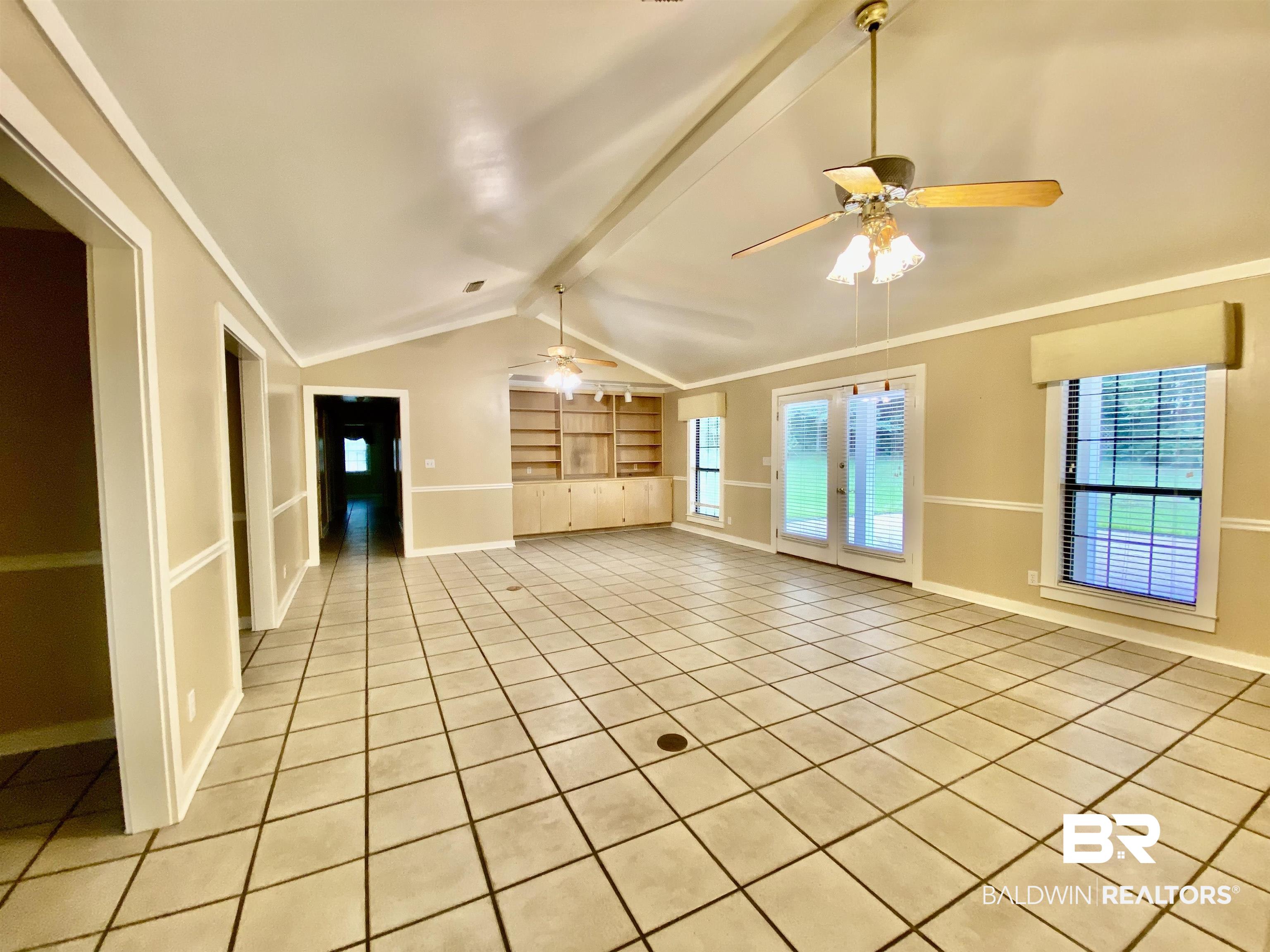 160 Mockingbird Lane Monroeville, AL 36460 - Photo 5 of 36 Unfurnished living room featuring light tile patterned floors, a ceiling fan, built in features, and plenty of natural light