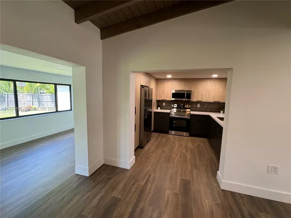 a view of a kitchen with wooden floor electronic appliances and stairs