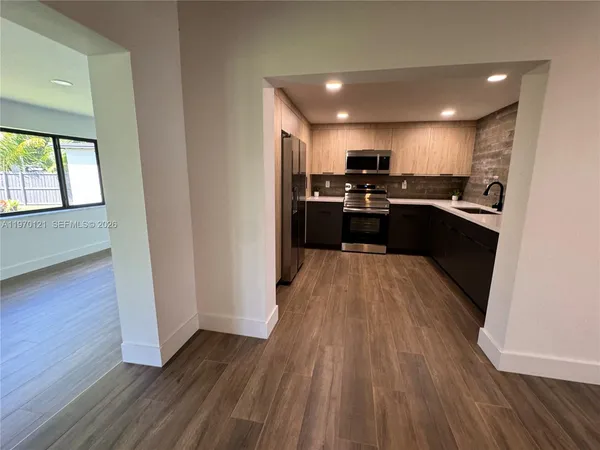 a large kitchen with a sink and wooden floor