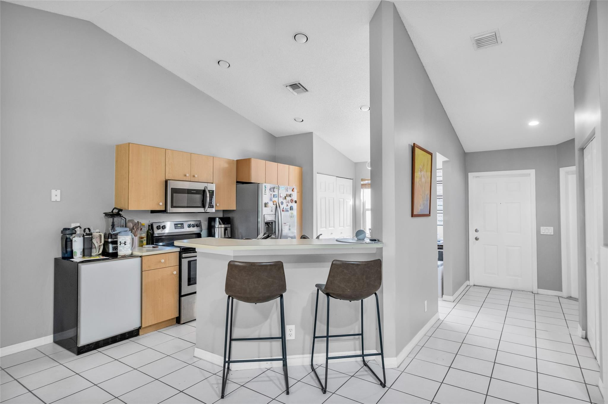 1665 Zenith Way Weston, FL 33327 - Photo 9 of 22 a kitchen with stainless steel appliances a stove a sink a refrigerator white cabinets with a dining table and chairs