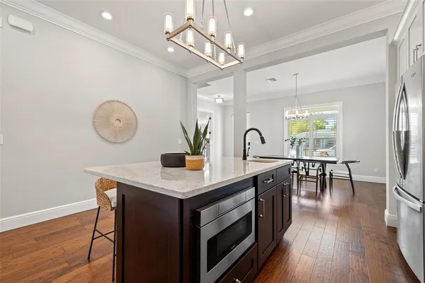 a kitchen with stainless steel appliances granite countertop a stove a sink dishwasher a dining table and chairs with wooden floor