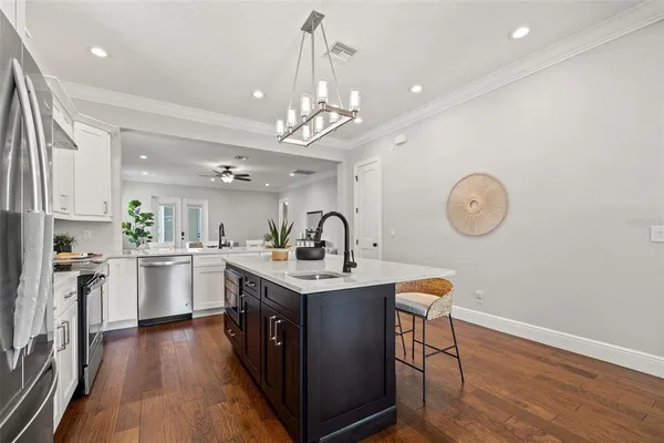 a kitchen with stainless steel appliances granite countertop a stove top oven a sink dishwasher and white cabinets with wooden floor