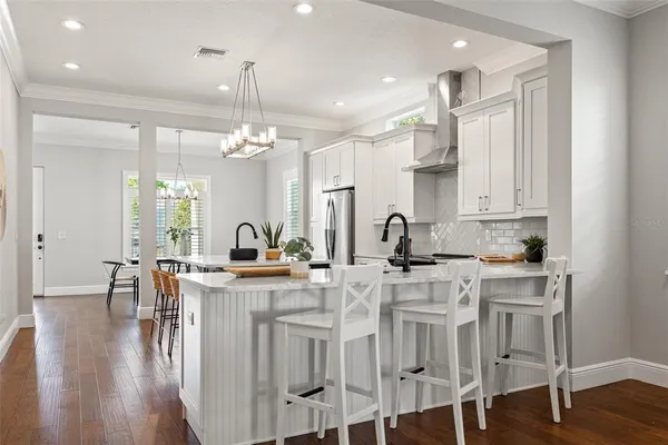 a kitchen with kitchen island granite countertop a table chairs stove a sink dishwasher and cabinets