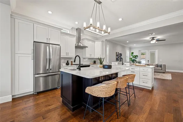 a kitchen with stainless steel appliances granite countertop a dining table chairs stove refrigerator and cabinets