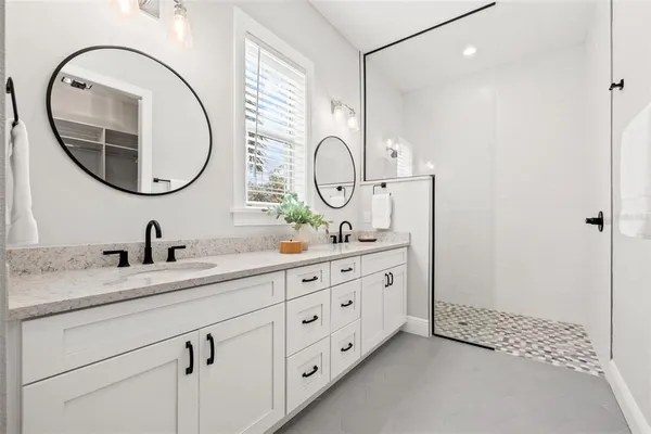 a bathroom with a granite countertop double vanity sink and a mirror