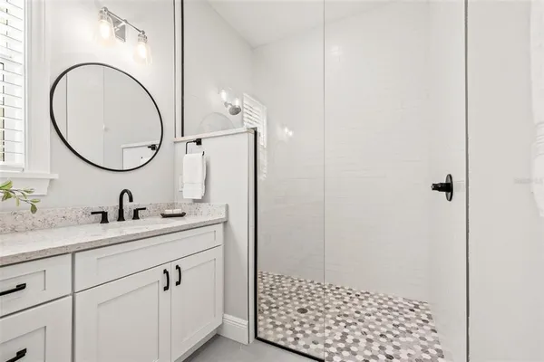 a bathroom with a granite countertop sink a mirror and a shower