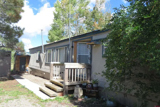 a view of a wooden house with a small yard and furniture