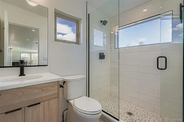 a bathroom with a shower sink vanity mirror and toilet