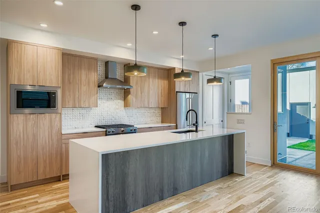 a kitchen with stainless steel appliances granite countertop a sink a stove a refrigerator and island with wooden floor