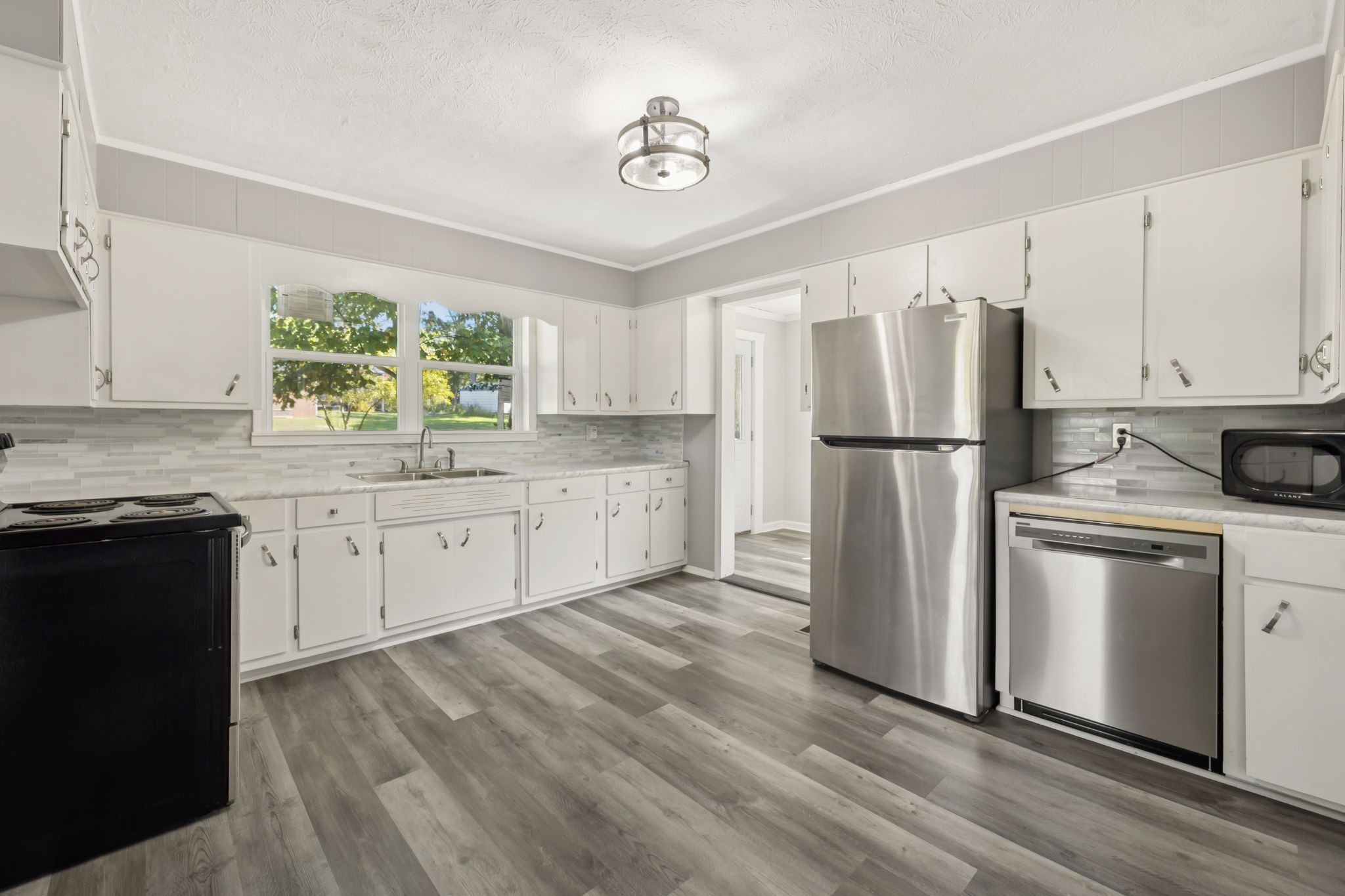 315 Ferguson Hill Road Lafayette, TN 37083 - Photo 14 of 29 a kitchen with a refrigerator a stove a sink and white cabinets with wooden floor
