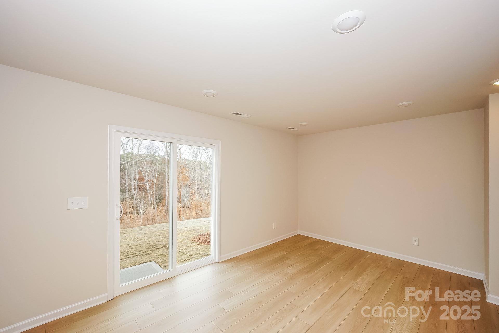 143 Arden Court Troutman, NC 28166 - Photo 9 of 18 an empty room with wooden floor and windows