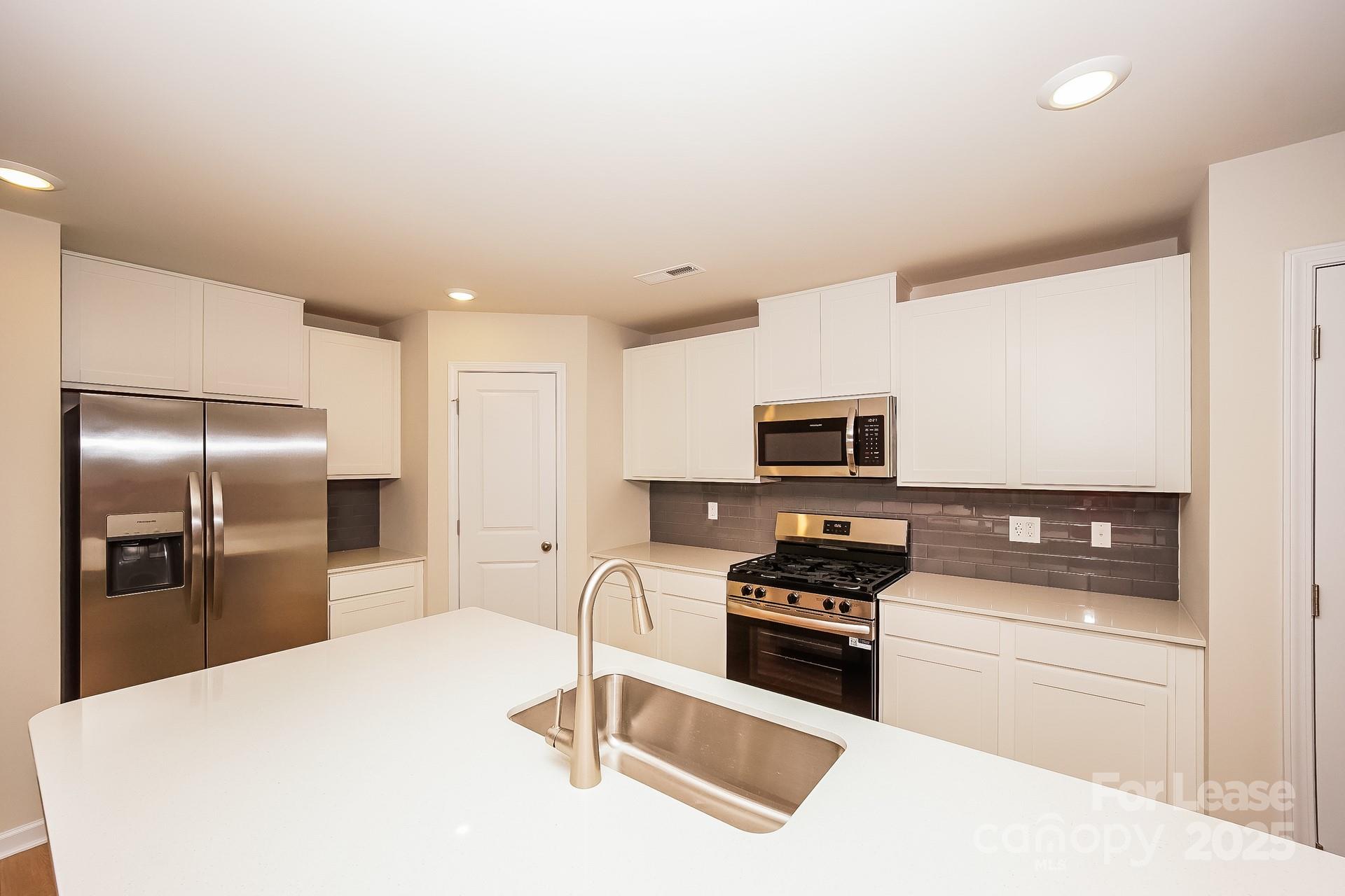 143 Arden Court Troutman, NC 28166 - Photo 10 of 18 a kitchen with granite countertop a refrigerator stove top oven and sink