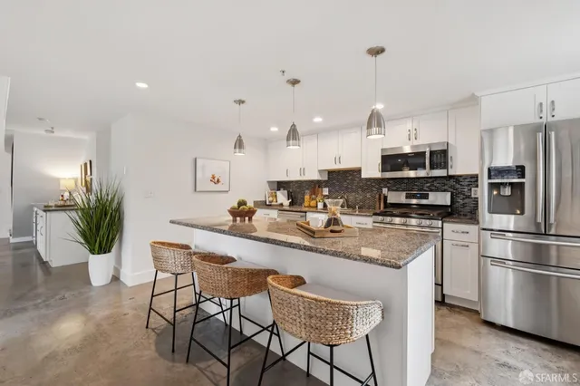 a kitchen with stainless steel appliances a sink a stove a microwave a refrigerator and cabinets