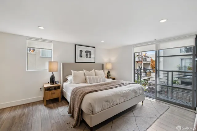 a bedroom with a bed a window and potted plant on the dresser