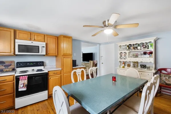 a kitchen with stainless steel appliances granite countertop a stove top oven a sink a dining table and chairs with wooden floor