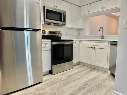 a kitchen with a refrigerator sink and white cabinets