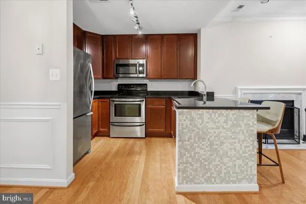 a kitchen with stainless steel appliances granite countertop a stove a sink dishwasher a microwave oven and a refrigerator with wooden floor