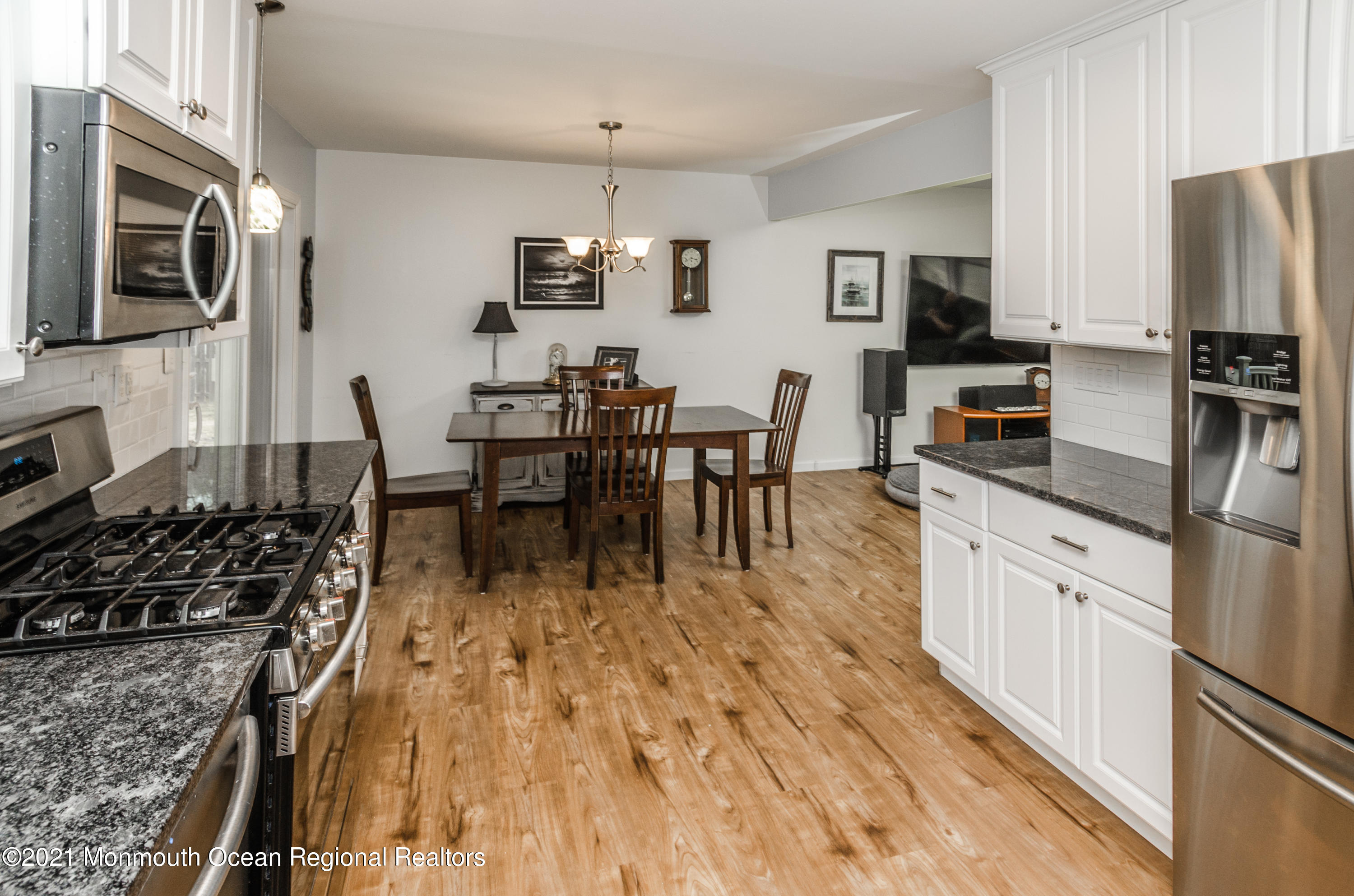 58 Pinewood Drive Brick, NJ 08724 - Photo 16 of 30 a kitchen with stainless steel appliances granite countertop a stove top oven a sink dishwasher a dining table and chairs with wooden floor