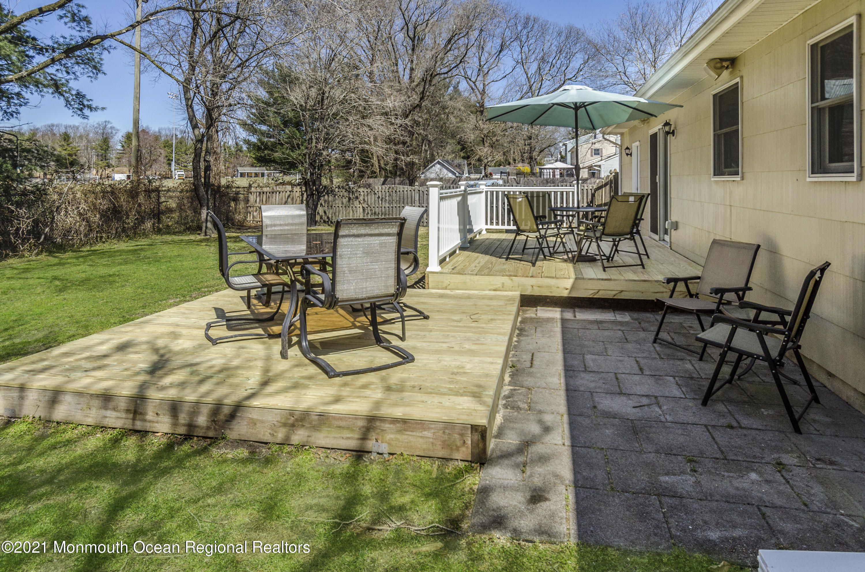 58 Pinewood Drive Brick, NJ 08724 - Photo 25 of 30 a view of a patio with table and chairs under an umbrella with a garden