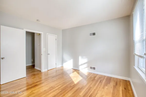 a view of empty room with wooden floor and fan