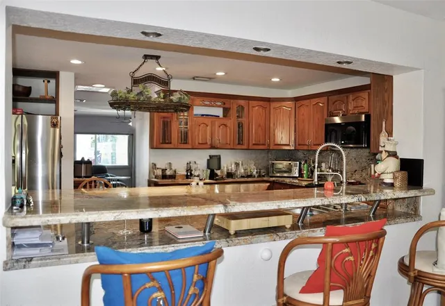 a kitchen with stainless steel appliances granite countertop a sink a stove and a wooden floors