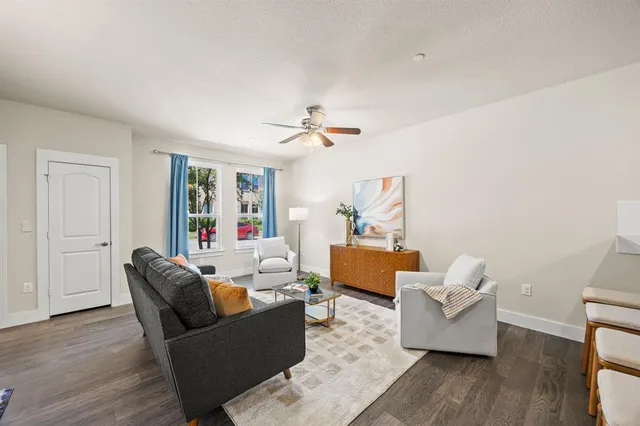 a view of an empty room with wooden floor and a ceiling fan