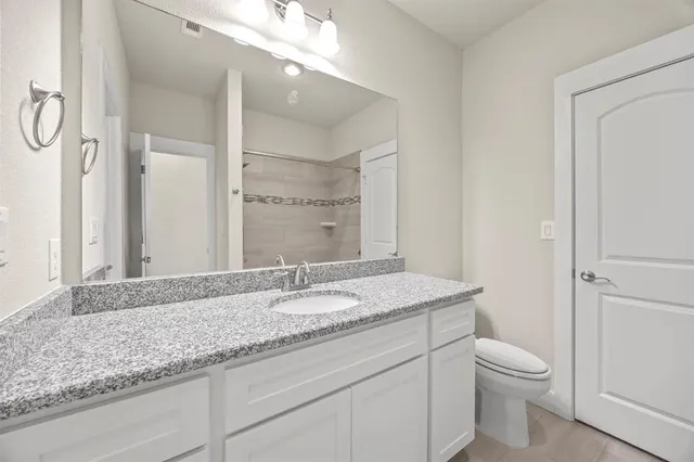 a bathroom with a granite countertop sink toilet and shower