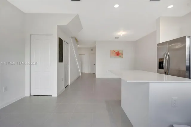 a view of a kitchen with refrigerator and white cabinets