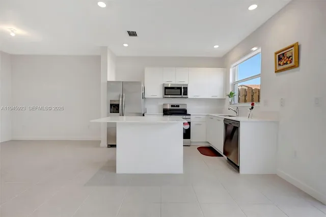 a kitchen with white cabinets and stainless steel appliances
