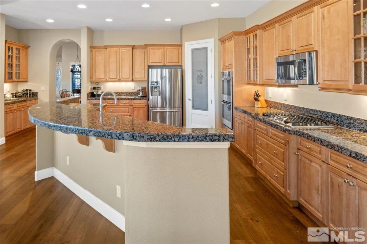 15185 Chateau Avenue Reno, NV 89511 - Photo 12 of 39 a kitchen with stainless steel appliances granite countertop a refrigerator a stove and a sink with wooden floor