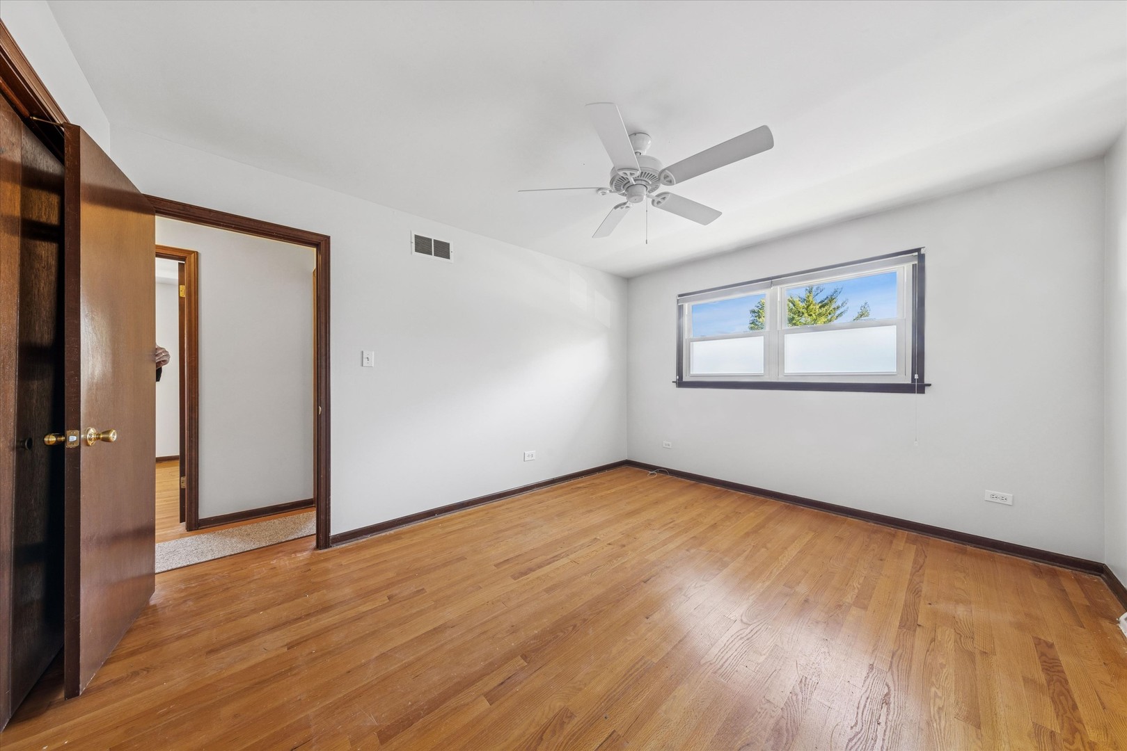 1310 Iroquois Lane Darien, IL 60561 - Photo 12 of 22 an empty room with wooden floor ceiling fan and windows