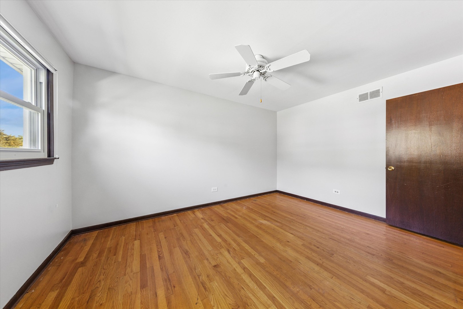 1310 Iroquois Lane Darien, IL 60561 - Photo 14 of 22 a view of an empty room with wooden floor and a window