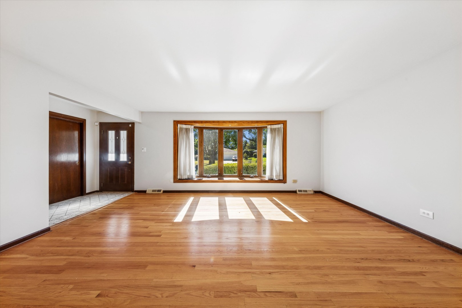 1310 Iroquois Lane Darien, IL 60561 - Photo 4 of 22 a view of an empty room with window and wooden floor