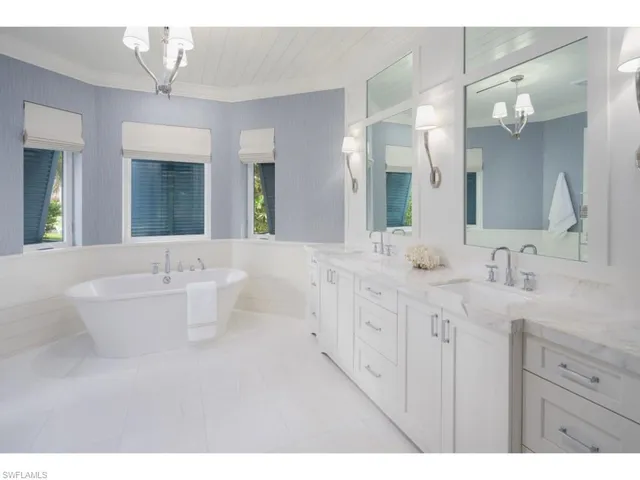 a bathroom with double vanity sinks a large mirror and a bathtub