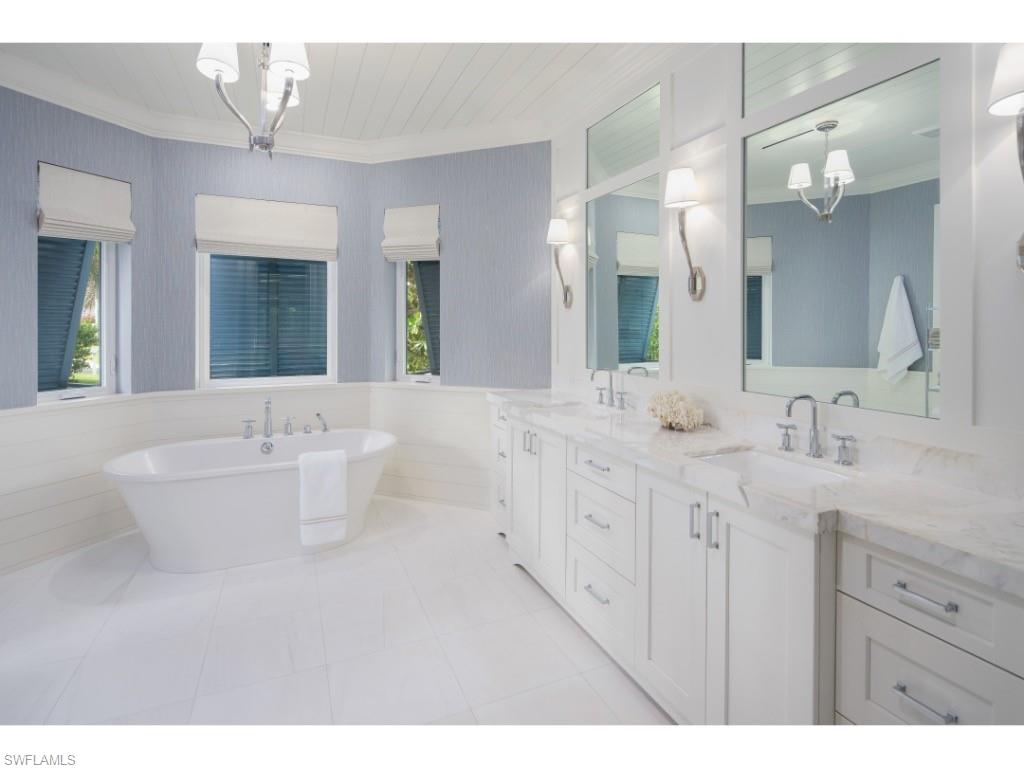 4042 Old Trail Way Naples, FL 34103 - Photo 9 of 20 a bathroom with double vanity sinks a large mirror and a bathtub