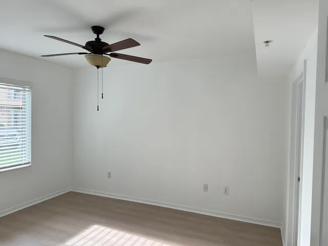 an empty room with a window and ceiling fan
