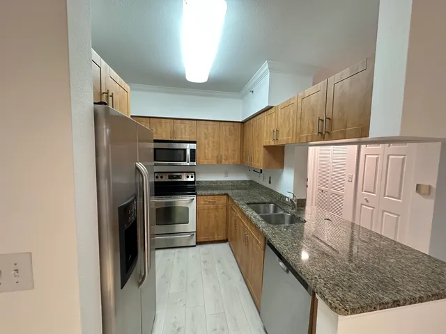 a kitchen with granite countertop a refrigerator and a sink