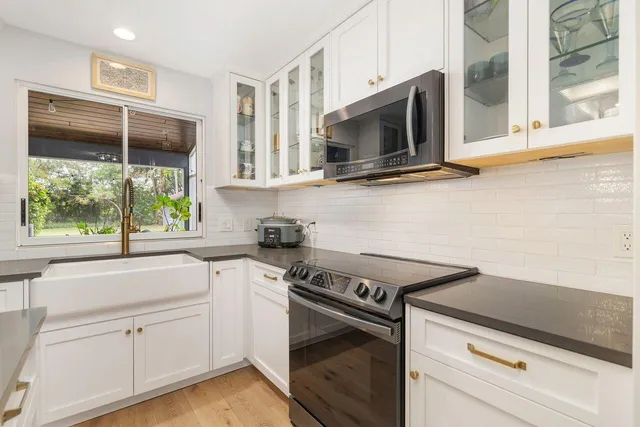 a kitchen with stainless steel appliances white cabinets and a stove top oven