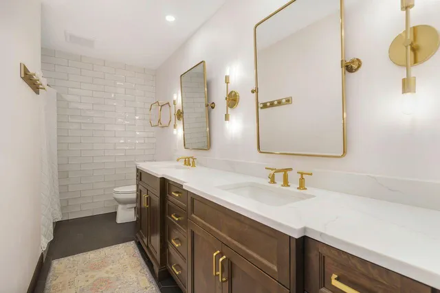 a bathroom with a double vanity sink toilet and mirror