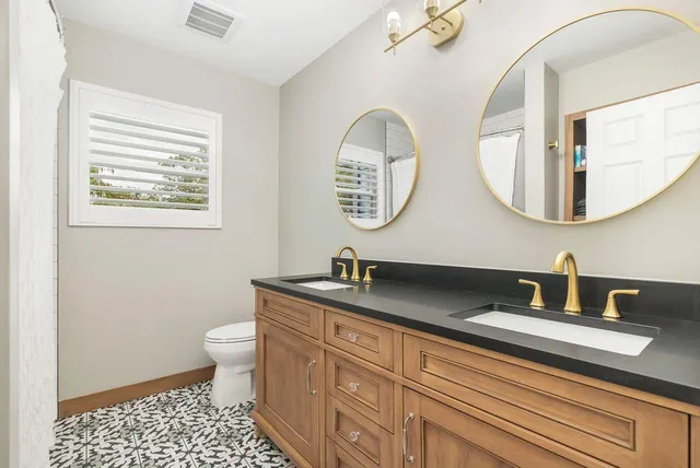 a bathroom with a granite countertop toilet a sink and mirror