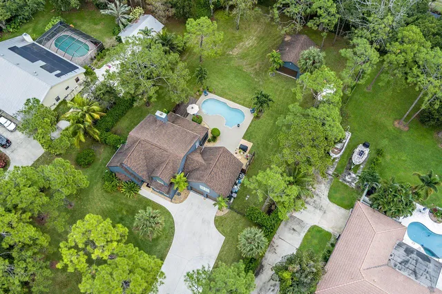 an aerial view of residential house with outdoor space and trees all around
