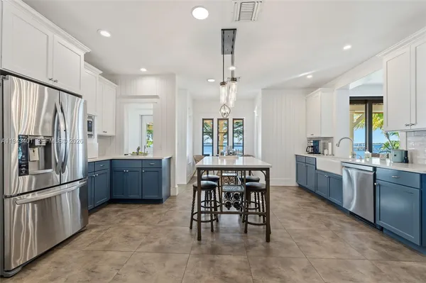 a kitchen with stainless steel appliances a dining table chairs stove refrigerator and cabinets
