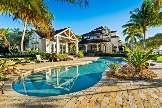 a view of a swimming pool with a yard and palm trees