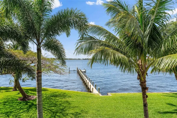 a view of a white house with a big yard and palm trees
