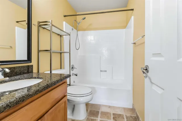 a bathroom with a granite countertop sink toilet and shower