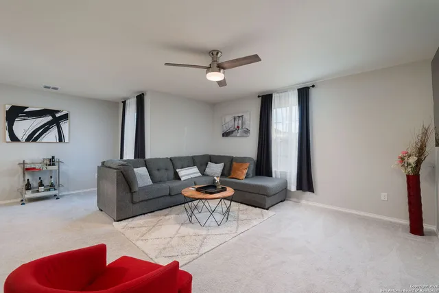 a living room with furniture and a ceiling fan