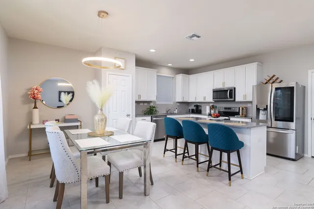a kitchen with a dining table chairs and refrigerator